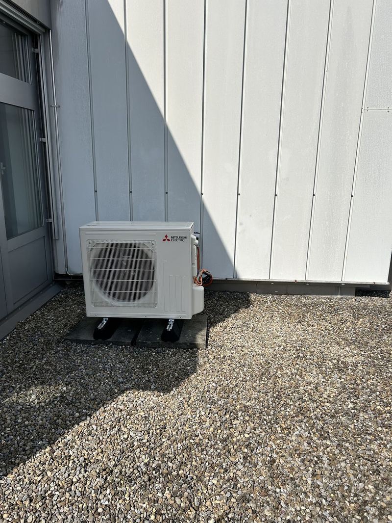 Aussengerät von Mitsubishi Electric auf einem Kiesbett an einer Fassade