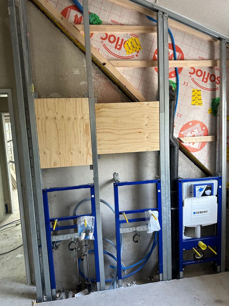 Eğimli çatı altında bir ön duvarda iki lavabo ve bir asma WC için Geberit Duofix elemanları